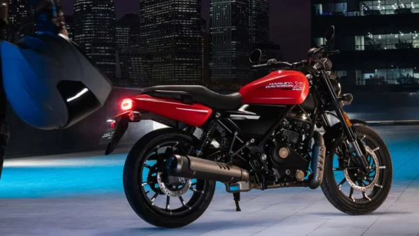 Harley-Davidson X440 vermelha vista de lado, com motor monocilíndrico de 440 cc, rodas de liga leve e escapamento preto, em cenário urbano noturno.