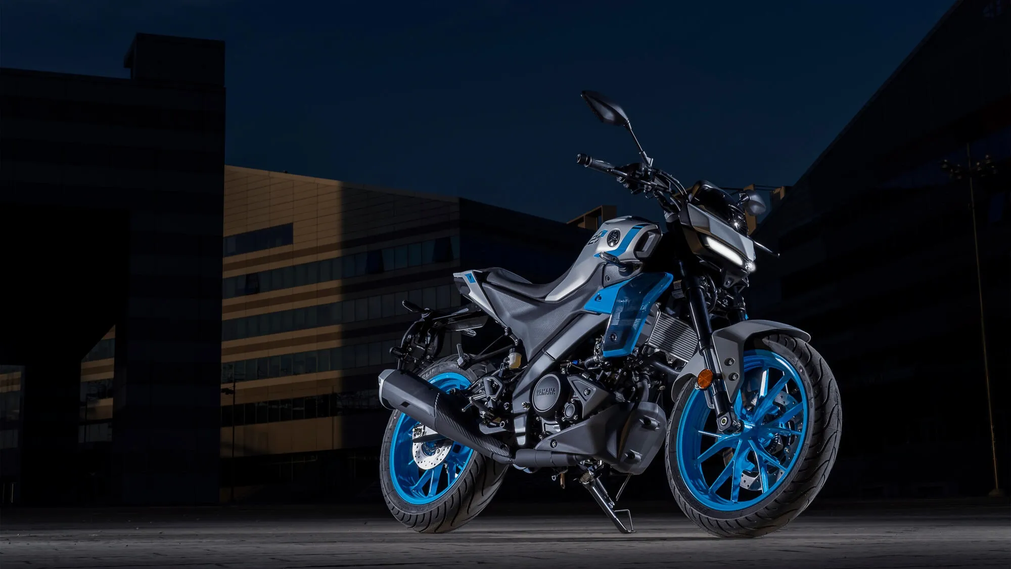 Yamaha MT-125 2027 na combinação azul e cinza, com rodas azuis, farol de LED e design esportivo, estacionada em cenário urbano.